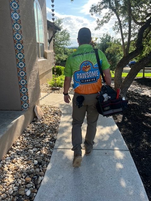 A person working in pawsome plumbing company walking outside the house with tools in his bag