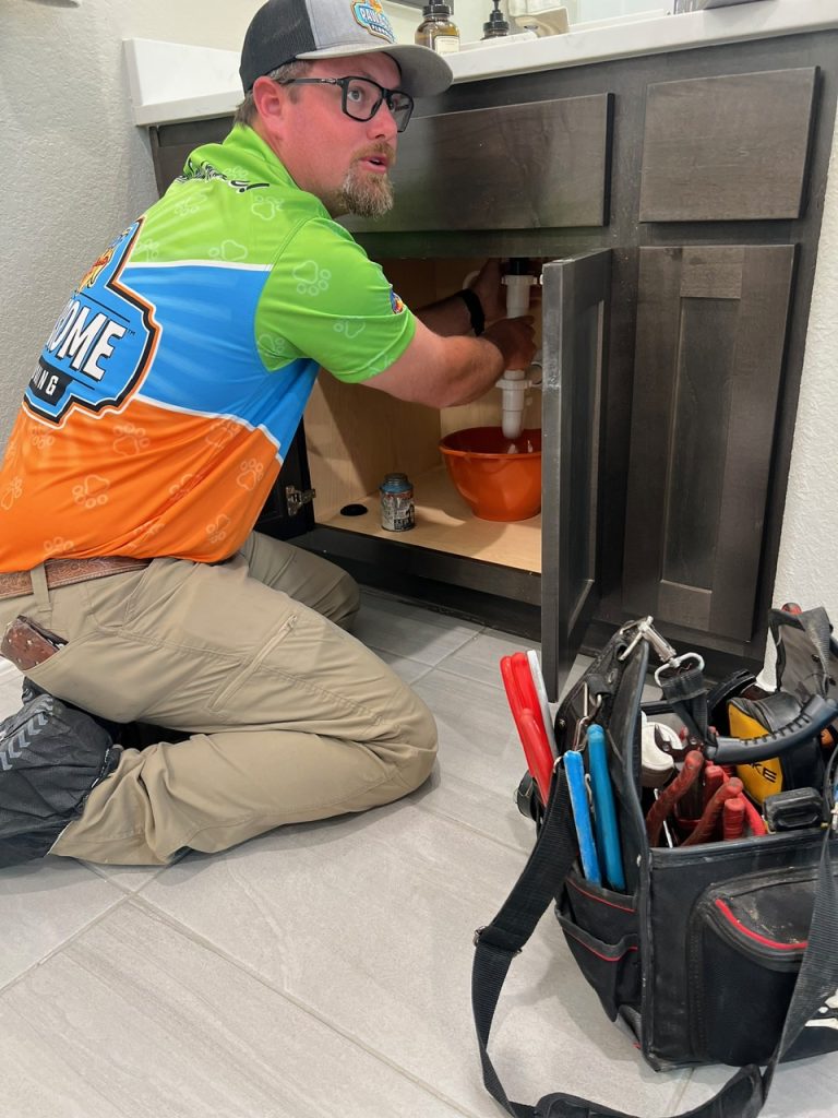 An image of a person working on plumbing under a sink